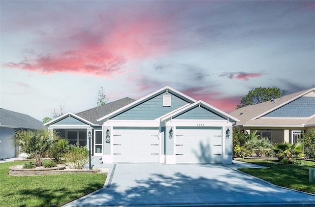 view of front facade with a garage, concrete driveway, a lawn, and stucco siding