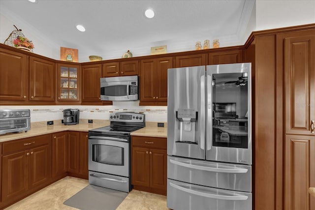 kitchen featuring light stone countertops, appliances with stainless steel finishes, backsplash, and crown molding