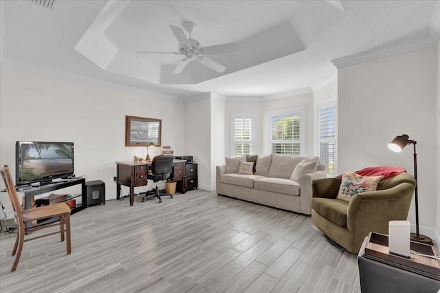 living room featuring ornamental molding, light hardwood / wood-style flooring, ceiling fan, and a tray ceiling