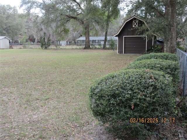 view of yard featuring an outbuilding, a detached garage, and fence