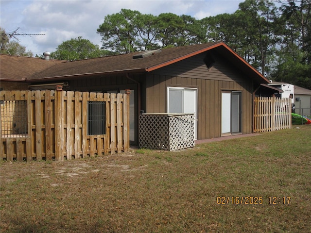 back of property featuring fence and a lawn