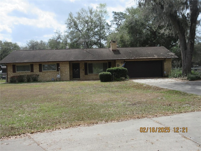 ranch-style home with driveway, a garage, a chimney, and a front lawn