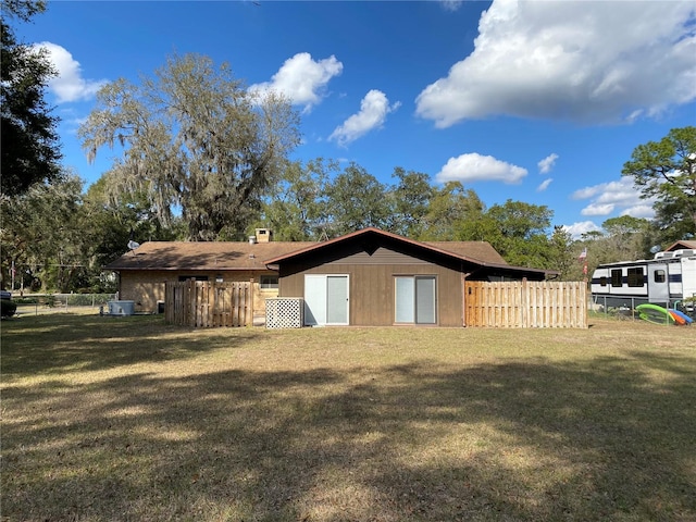 rear view of property featuring a yard and fence