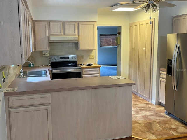 kitchen with appliances with stainless steel finishes, light countertops, a sink, and under cabinet range hood