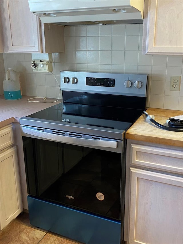 kitchen with stainless steel electric stove, light countertops, backsplash, light brown cabinets, and under cabinet range hood