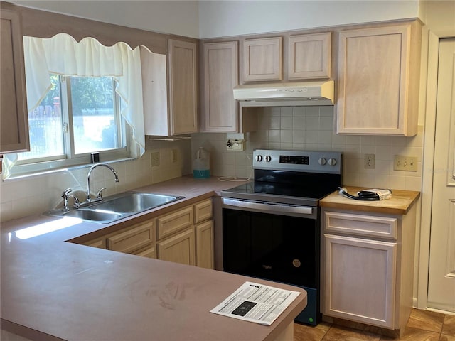 kitchen with stainless steel electric range oven, light countertops, light brown cabinetry, a sink, and under cabinet range hood