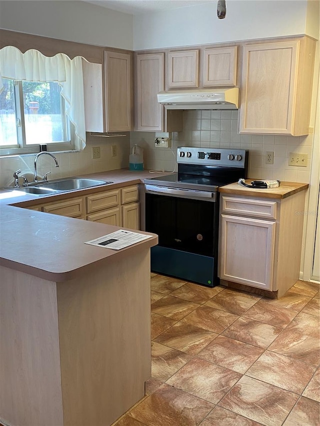 kitchen with electric stove, light countertops, light brown cabinets, a sink, and under cabinet range hood