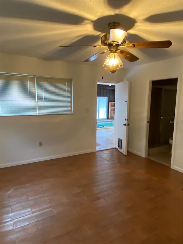 empty room with ceiling fan, wood finished floors, and baseboards