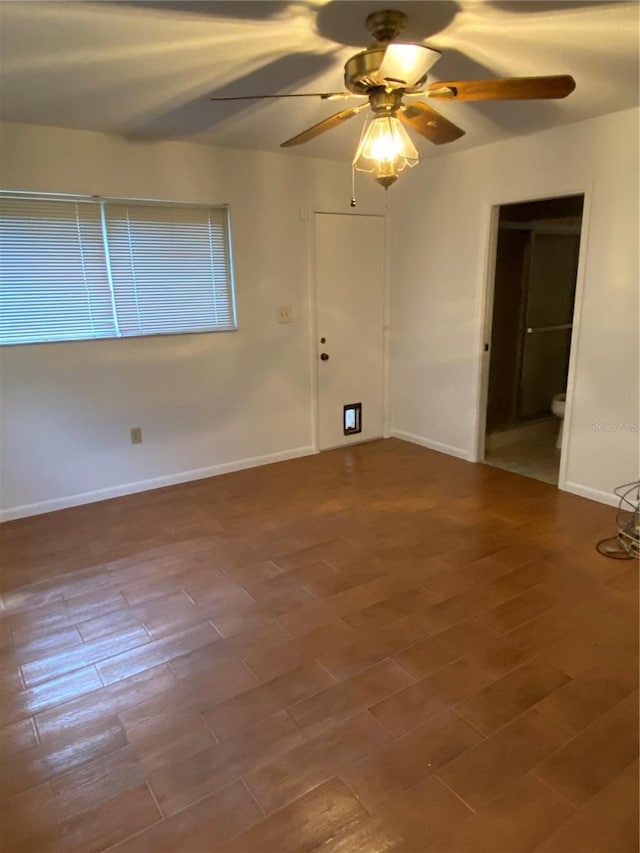 spare room featuring wood finished floors, a ceiling fan, and baseboards