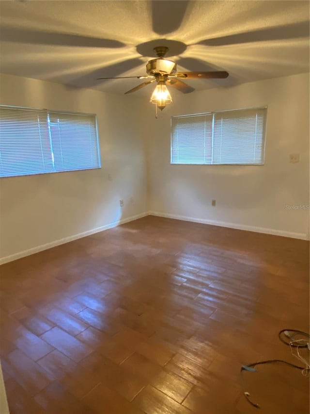 empty room with ceiling fan, baseboards, and wood finished floors