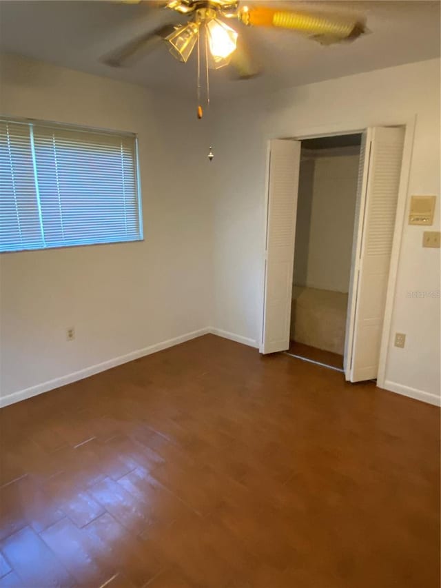 unfurnished bedroom with ceiling fan, dark wood-type flooring, a closet, and baseboards