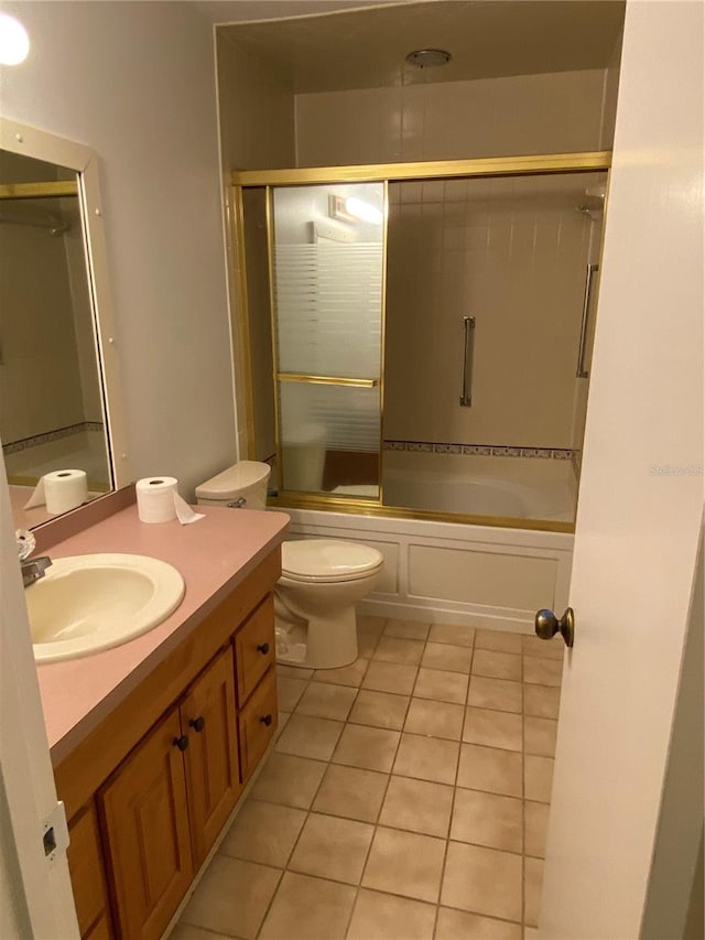 bathroom with toilet, shower / bath combination with glass door, tile patterned flooring, and vanity