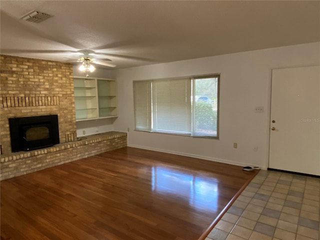 unfurnished living room with baseboards, a fireplace, visible vents, and wood finished floors