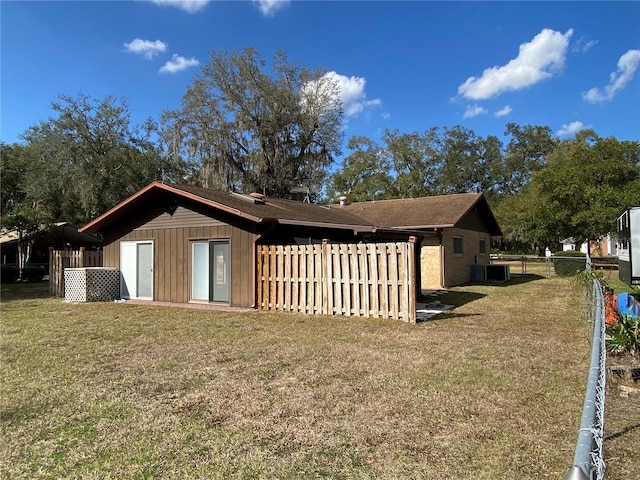 view of side of property featuring a yard, fence, and central air condition unit