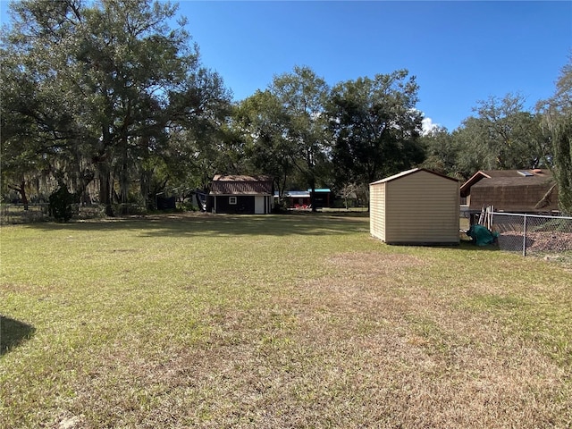 view of yard with fence, a storage unit, and an outbuilding