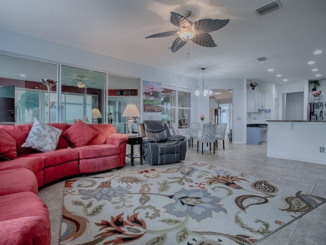 tiled living room with a healthy amount of sunlight and ceiling fan with notable chandelier