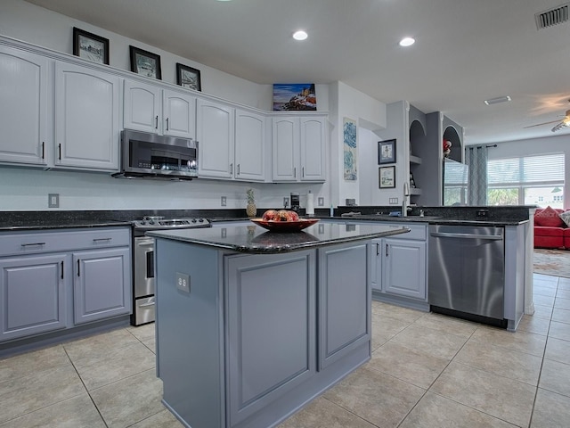 kitchen featuring light tile patterned flooring, gray cabinets, kitchen peninsula, a kitchen island, and stainless steel appliances