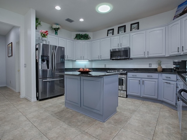 kitchen with stainless steel appliances, dark stone countertops, a kitchen island, and light tile patterned floors