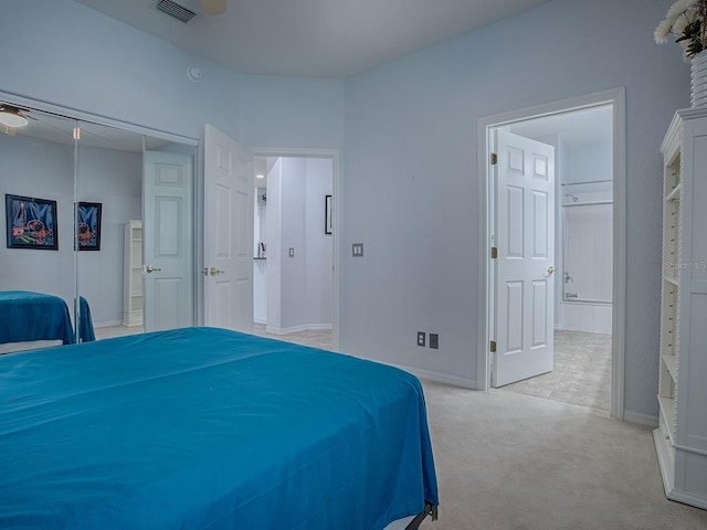 bedroom featuring ensuite bathroom, light carpet, and a closet