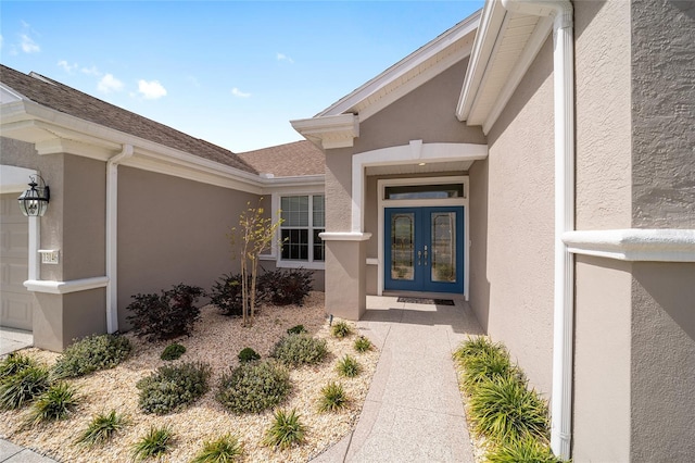 entrance to property with a garage, french doors, roof with shingles, and stucco siding