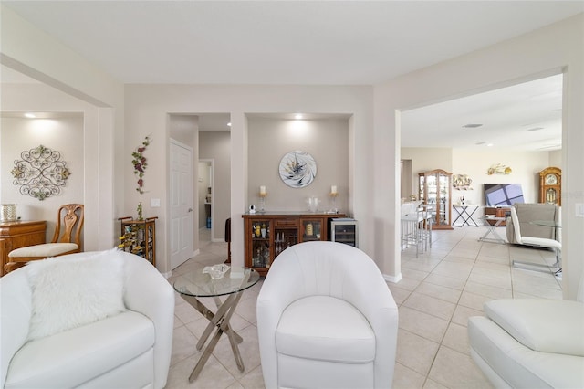 living room with wine cooler, baseboards, light tile patterned flooring, and a dry bar