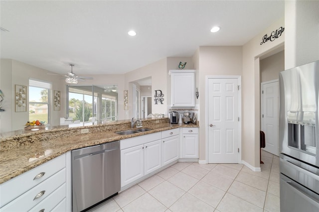 kitchen featuring stainless steel appliances, light tile patterned flooring, white cabinets, a sink, and light stone countertops