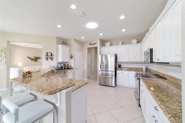 kitchen featuring white cabinetry, visible vents, stainless steel appliances, and a kitchen breakfast bar