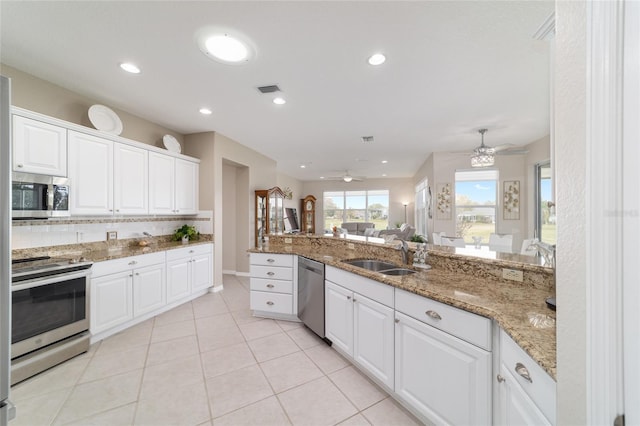 kitchen with stainless steel appliances, tasteful backsplash, a sink, and white cabinetry