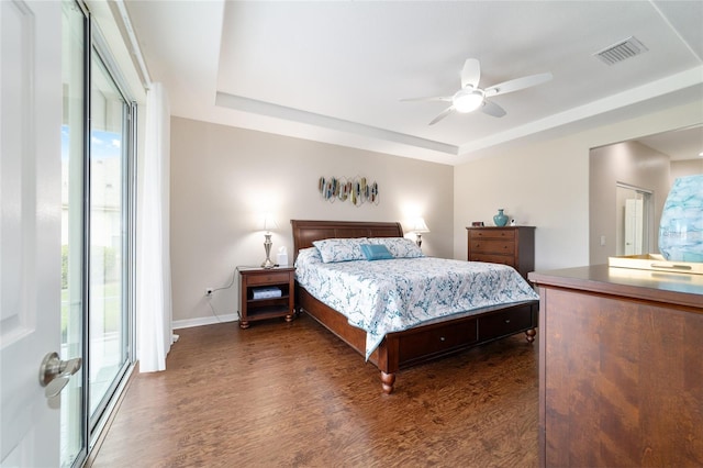 bedroom featuring ceiling fan, wood finished floors, visible vents, baseboards, and a raised ceiling