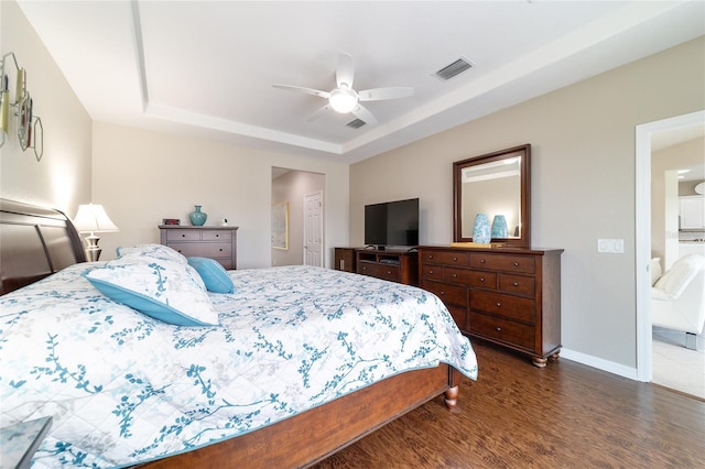 bedroom with baseboards, visible vents, a raised ceiling, ceiling fan, and dark wood-type flooring