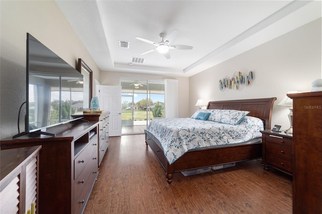 bedroom featuring dark wood-type flooring, a raised ceiling, visible vents, and access to exterior