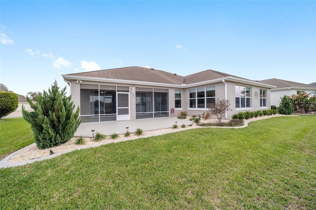 rear view of house featuring stucco siding, a sunroom, and a yard