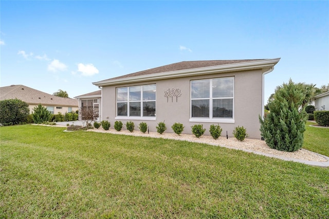 rear view of house with a lawn and stucco siding