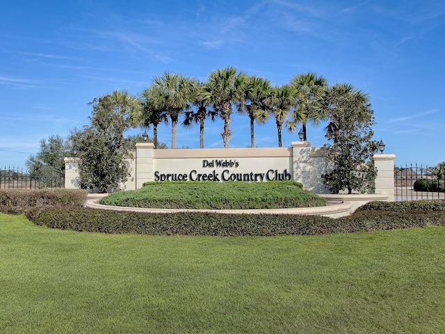 community / neighborhood sign featuring fence and a lawn