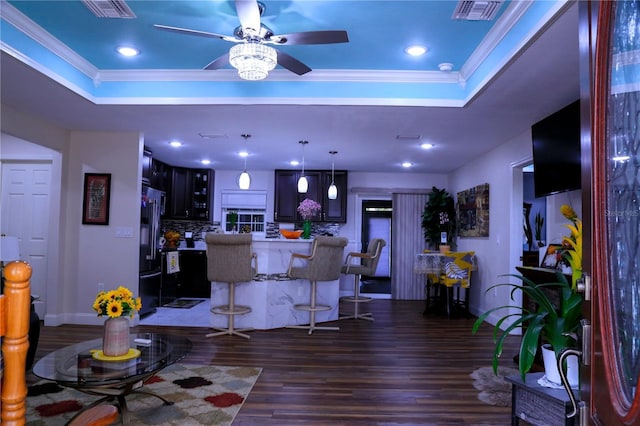 living room featuring a tray ceiling, ornamental molding, dark hardwood / wood-style floors, and ceiling fan