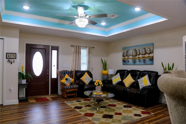 living room with a tray ceiling, ornamental molding, ceiling fan, and dark hardwood / wood-style flooring