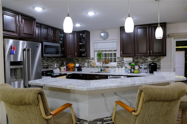 kitchen with appliances with stainless steel finishes, sink, hanging light fixtures, and a kitchen bar