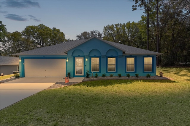 ranch-style home with a front lawn, concrete driveway, roof with shingles, stucco siding, and an attached garage