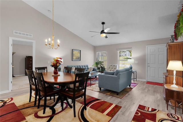 dining space with visible vents, baseboards, high vaulted ceiling, light wood-style flooring, and ceiling fan with notable chandelier