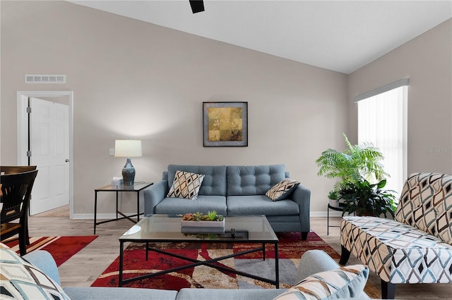 living room with visible vents, lofted ceiling, baseboards, and wood finished floors