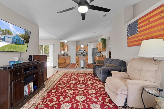 living room featuring visible vents, lofted ceiling, a textured ceiling, and ceiling fan