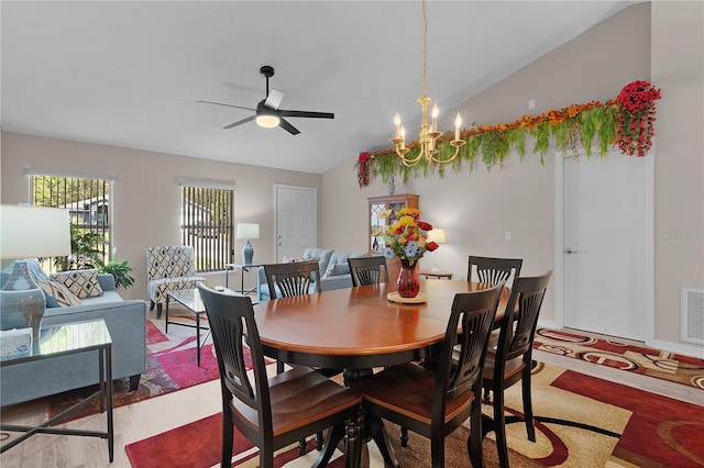 dining space with vaulted ceiling, wood finished floors, ceiling fan with notable chandelier, and visible vents