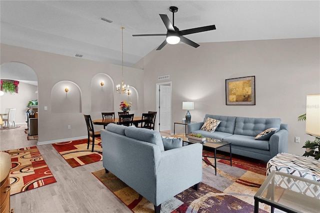 living area with ceiling fan with notable chandelier, wood finished floors, visible vents, and arched walkways