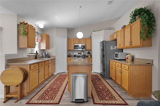 kitchen featuring a sink, light wood-style flooring, a kitchen island with sink, and stainless steel appliances