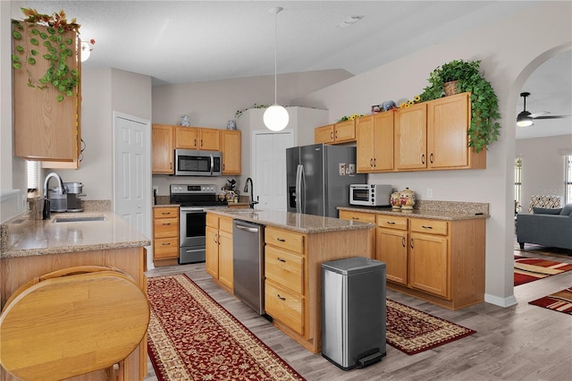 kitchen featuring light stone counters, a toaster, stainless steel appliances, and a sink