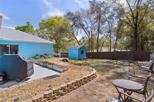 view of yard with a storage unit, an outdoor structure, a fenced backyard, and a vegetable garden