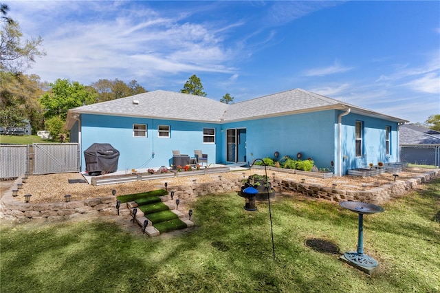 rear view of property featuring fence, roof with shingles, stucco siding, a yard, and a gate