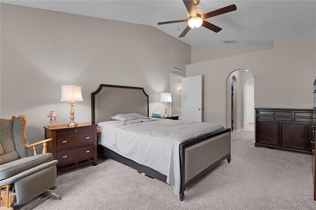 bedroom with arched walkways, visible vents, light colored carpet, and lofted ceiling