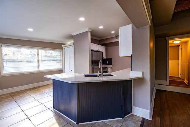 kitchen with white cabinetry, black refrigerator, crown molding, and kitchen peninsula