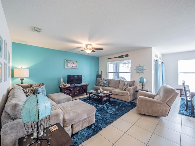 living room with light tile patterned floors, ceiling fan, a textured ceiling, and visible vents